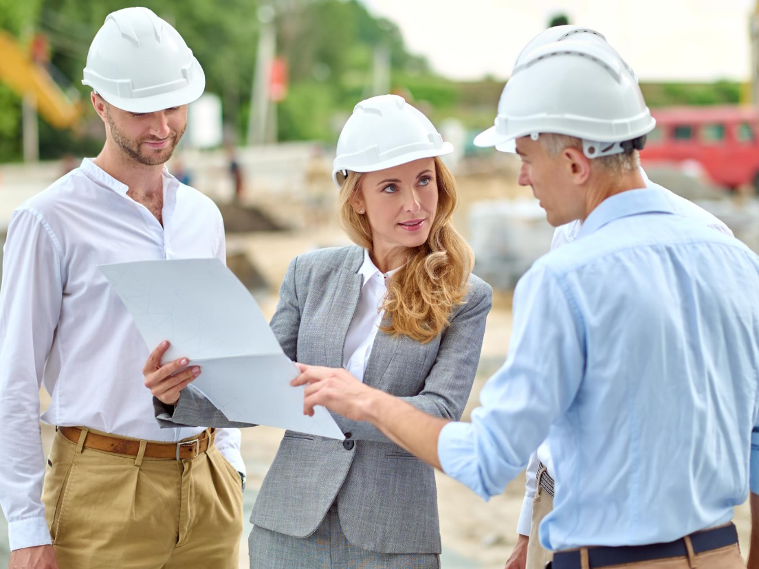 Architectes discutant plans sur un chantier.