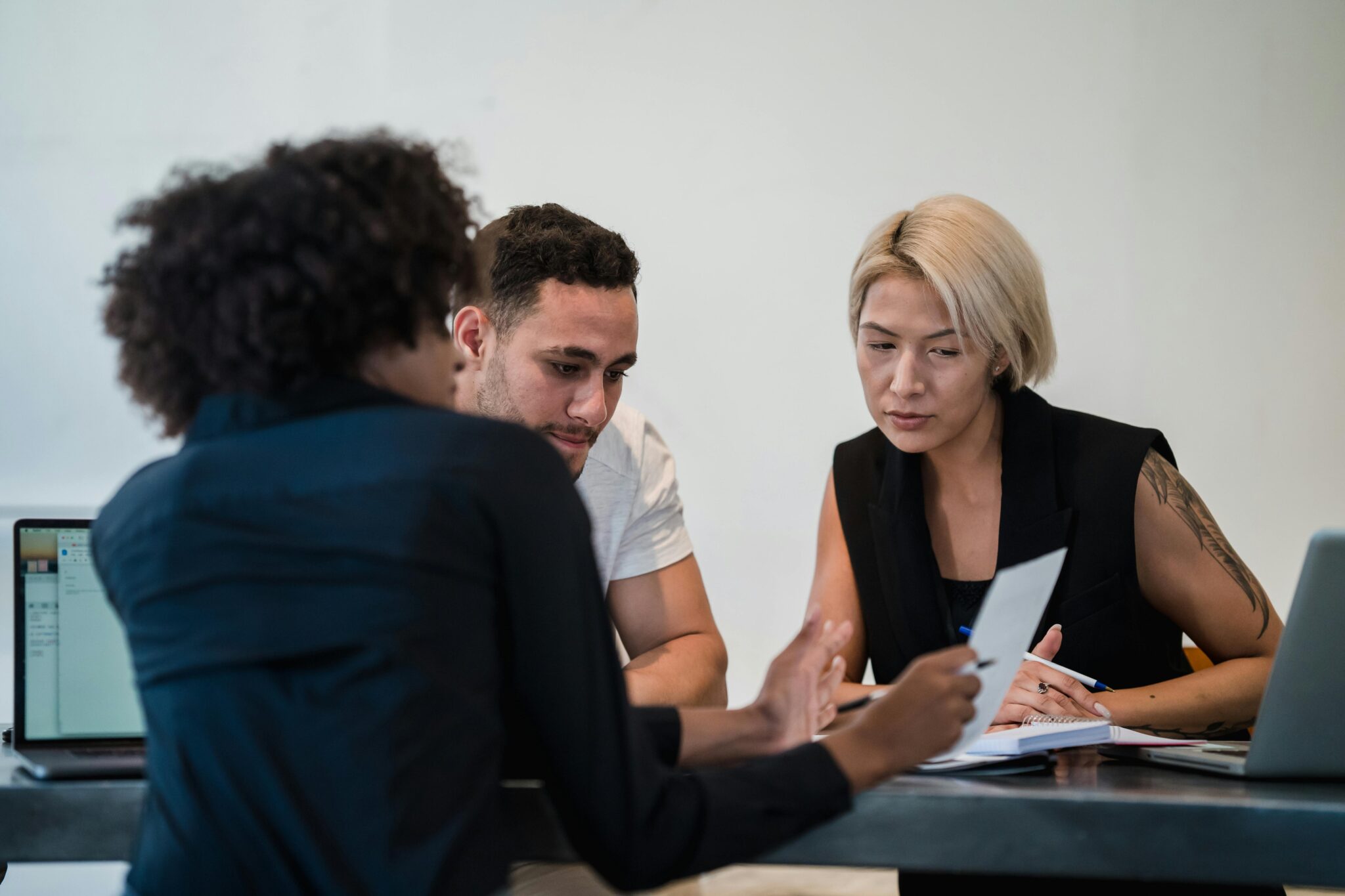 Réunion d'équipe autour d'une table avec ordinateurs.